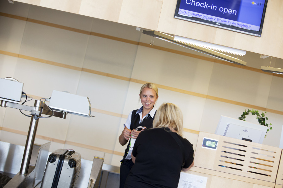 Check-in agent checkar in en kvinnlig resenärs väska